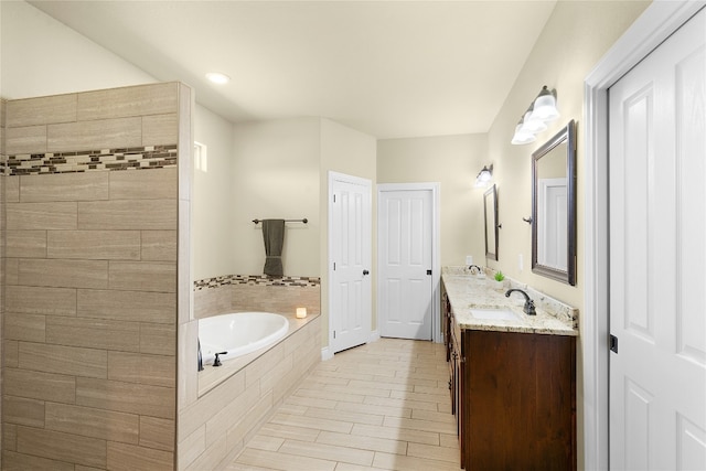 bathroom featuring wood-type flooring, vanity, and tiled bath