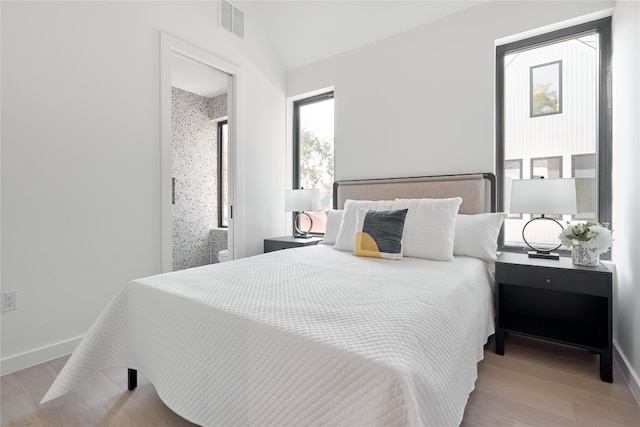 bedroom with light hardwood / wood-style floors, multiple windows, and lofted ceiling