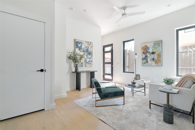 living area featuring a wealth of natural light, ceiling fan, and light wood-type flooring