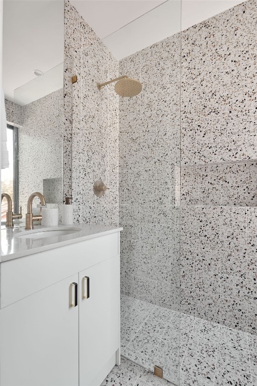 bathroom with a tile shower, vanity, and tile walls