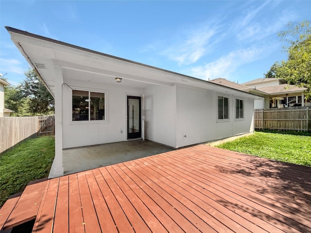 back of property with a lawn, a patio area, and a deck