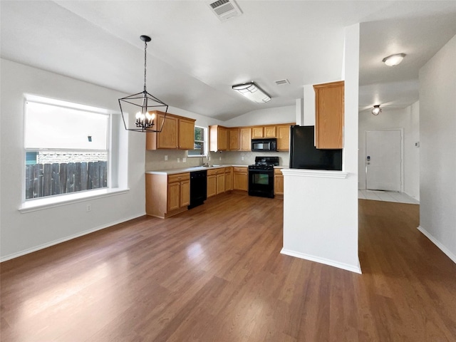 kitchen featuring a notable chandelier, black appliances, vaulted ceiling, and plenty of natural light