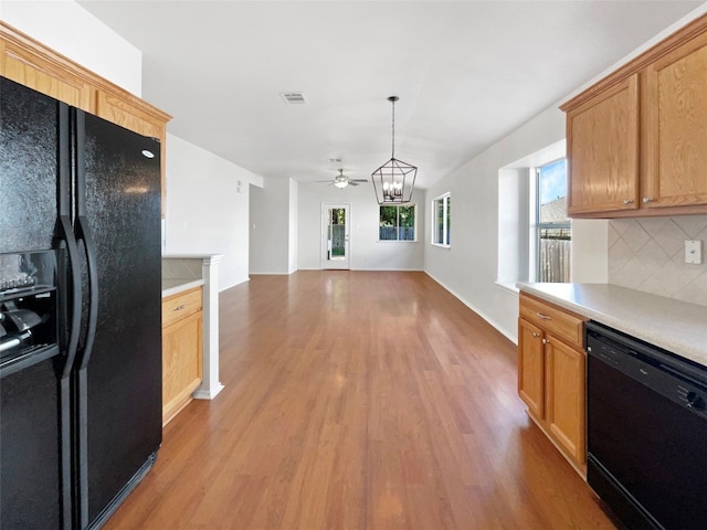 kitchen featuring light wood-type flooring, ceiling fan with notable chandelier, black appliances, backsplash, and decorative light fixtures