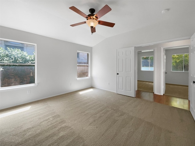 carpeted empty room featuring ceiling fan, plenty of natural light, and vaulted ceiling