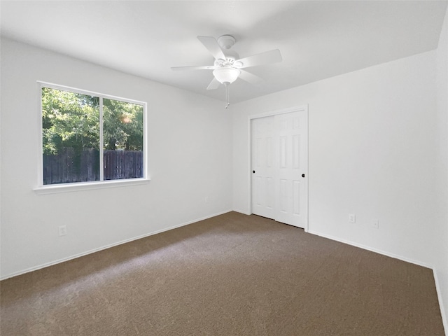 spare room featuring dark carpet and ceiling fan