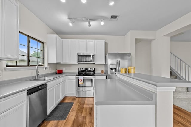 kitchen with white cabinets, appliances with stainless steel finishes, a center island, and sink