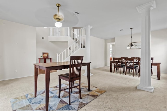 carpeted dining area featuring ceiling fan with notable chandelier and ornate columns