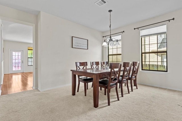 dining area with light carpet and an inviting chandelier