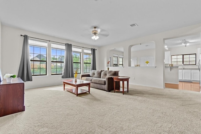 carpeted living room with ceiling fan