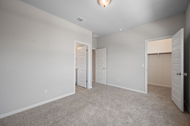 unfurnished bedroom with light colored carpet, a spacious closet, and a closet