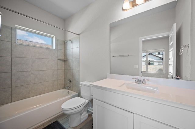 full bathroom with toilet, tiled shower / bath combo, a healthy amount of sunlight, and vanity