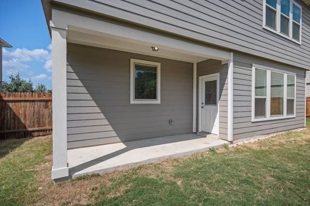 view of exterior entry featuring a patio area and a yard