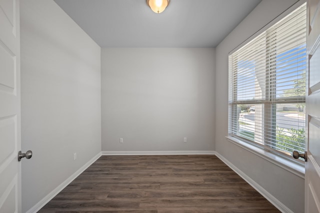 empty room with dark hardwood / wood-style flooring and plenty of natural light