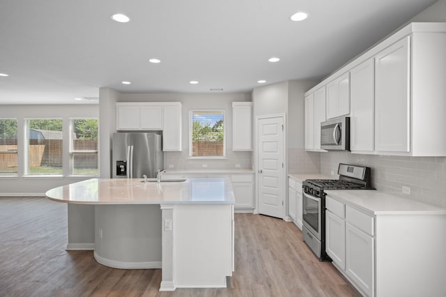 kitchen featuring stainless steel appliances, light wood-type flooring, a kitchen island with sink, white cabinetry, and sink