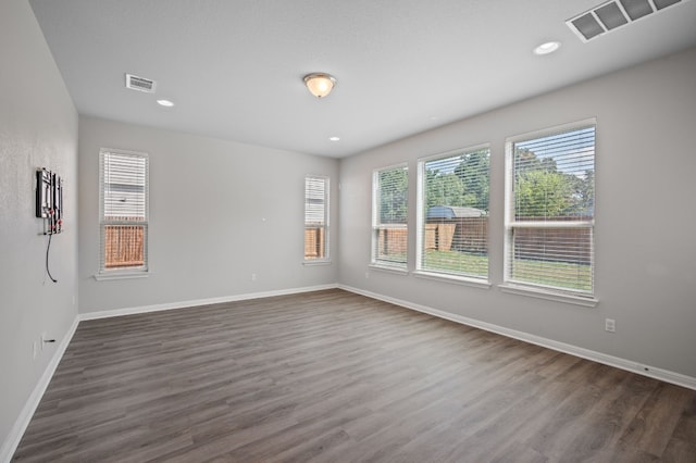 empty room with a wealth of natural light and dark hardwood / wood-style floors