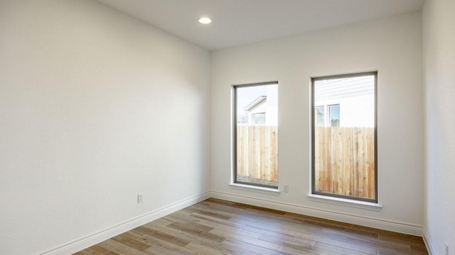 spare room with recessed lighting, baseboards, and wood finished floors