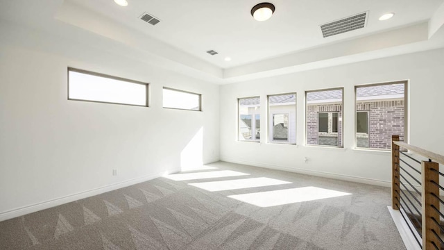 unfurnished room with baseboards, visible vents, and a tray ceiling