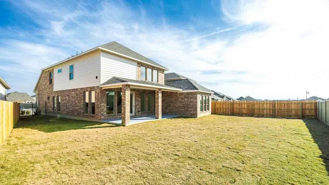 rear view of house with a patio area, a yard, and a fenced backyard