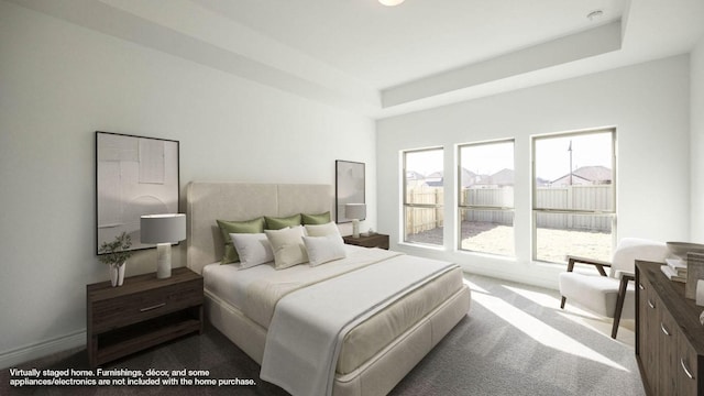 bedroom featuring a raised ceiling, dark carpet, and baseboards