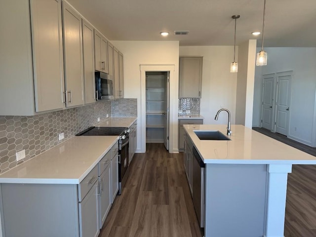 kitchen with pendant lighting, gray cabinetry, a kitchen island with sink, sink, and stainless steel appliances