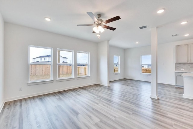 unfurnished living room featuring visible vents, light wood-style floors, and a healthy amount of sunlight