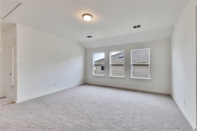 unfurnished room featuring visible vents, lofted ceiling, light colored carpet, and baseboards