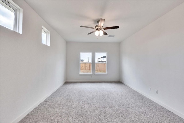 unfurnished room featuring light colored carpet, baseboards, a wealth of natural light, and ceiling fan