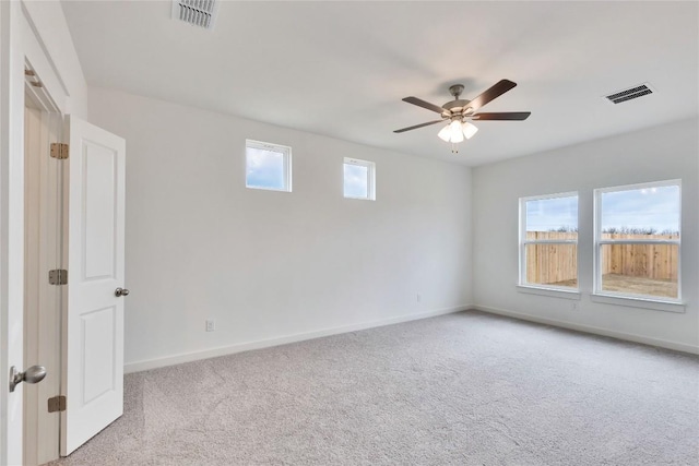 carpeted spare room featuring visible vents, a ceiling fan, and baseboards