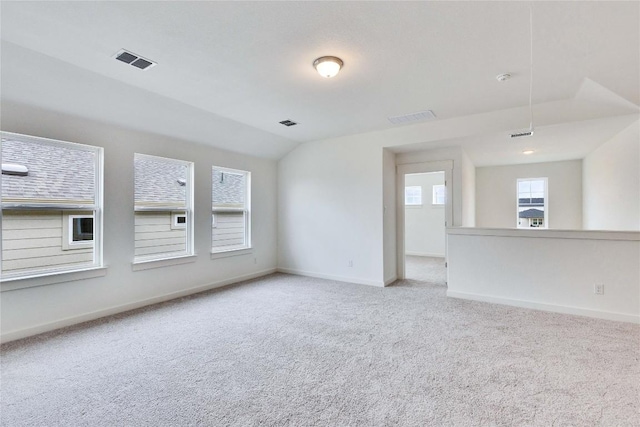 spare room with vaulted ceiling, visible vents, baseboards, and carpet floors