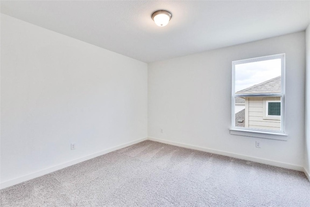 carpeted empty room featuring baseboards