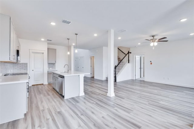 kitchen featuring a sink, decorative backsplash, visible vents, and open floor plan