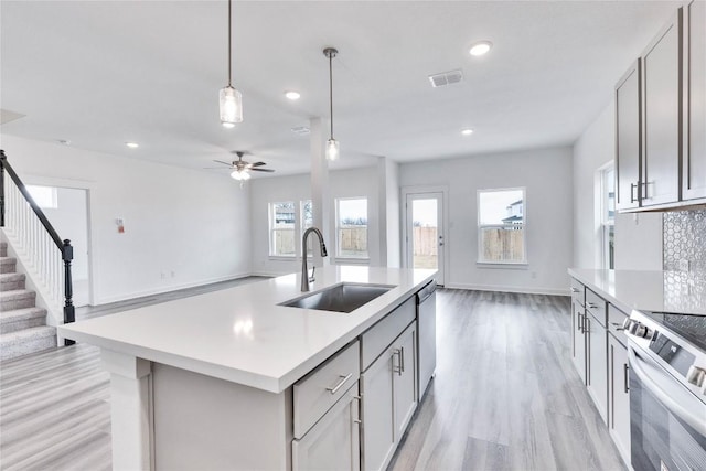 kitchen with a sink, open floor plan, stainless steel appliances, light countertops, and a healthy amount of sunlight