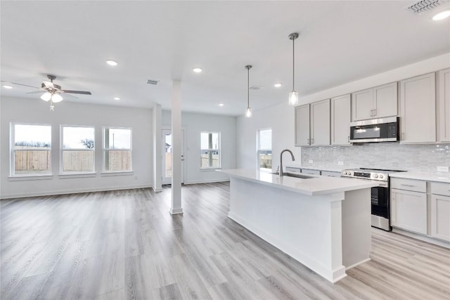 kitchen featuring visible vents, gray cabinets, a sink, stainless steel appliances, and open floor plan