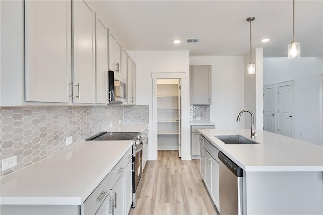 kitchen with visible vents, a sink, backsplash, light wood-style floors, and appliances with stainless steel finishes