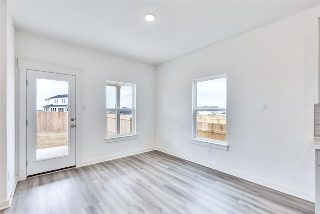 unfurnished room featuring baseboards and light wood-style floors