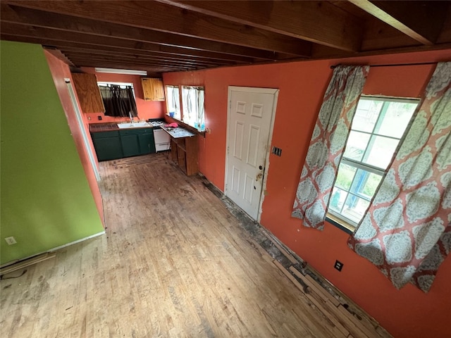 interior space with light wood-type flooring, sink, beamed ceiling, and a wealth of natural light