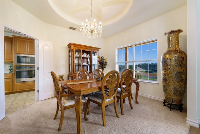 dining area featuring a raised ceiling, light carpet, and a notable chandelier