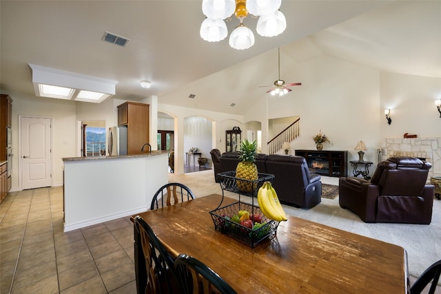 dining room with sink, ceiling fan with notable chandelier, light tile patterned floors, and high vaulted ceiling