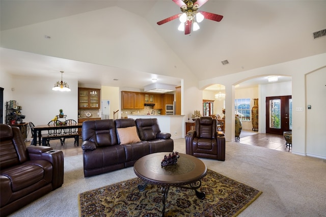 living room featuring ceiling fan with notable chandelier, light colored carpet, and high vaulted ceiling