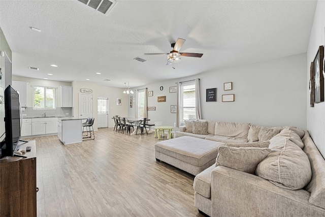 living room with light hardwood / wood-style floors, a textured ceiling, and ceiling fan