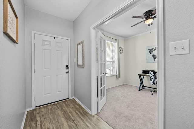 carpeted foyer featuring ceiling fan and ornamental molding