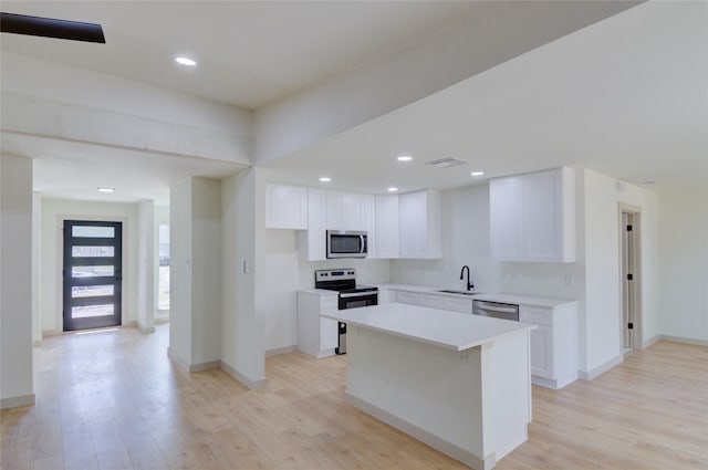 kitchen with a kitchen island, appliances with stainless steel finishes, sink, and white cabinetry