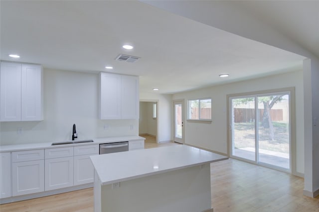 kitchen featuring white cabinets, sink, light wood-type flooring, and stainless steel dishwasher