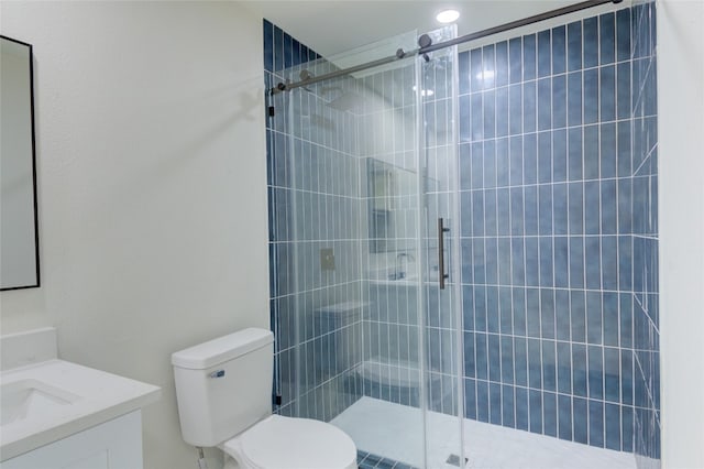 bathroom with a shower with shower door, vanity, and toilet