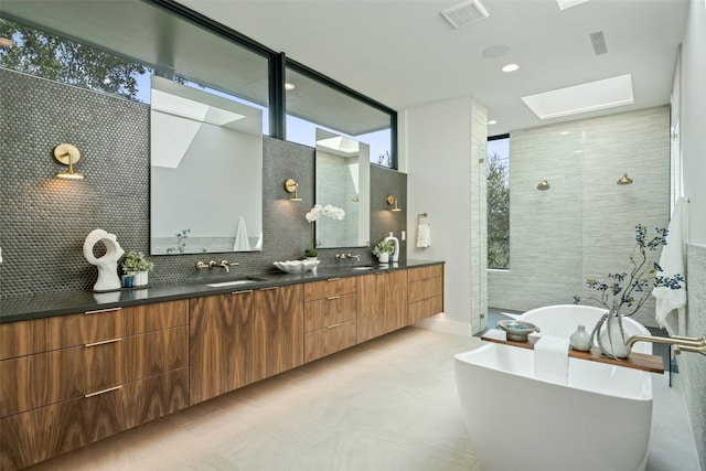 bathroom with shower with separate bathtub, vanity, a skylight, and backsplash