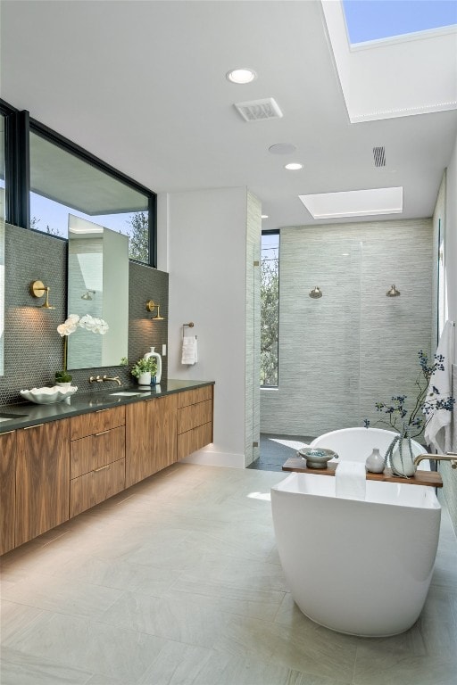 bathroom featuring separate shower and tub, a skylight, tasteful backsplash, and vanity