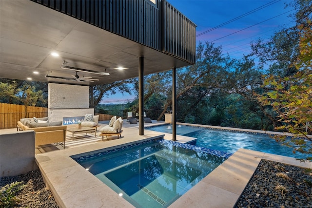 pool at dusk featuring outdoor lounge area, ceiling fan, a patio area, and an in ground hot tub