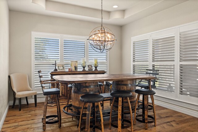 dining room featuring an inviting chandelier, a raised ceiling, and dark hardwood / wood-style floors