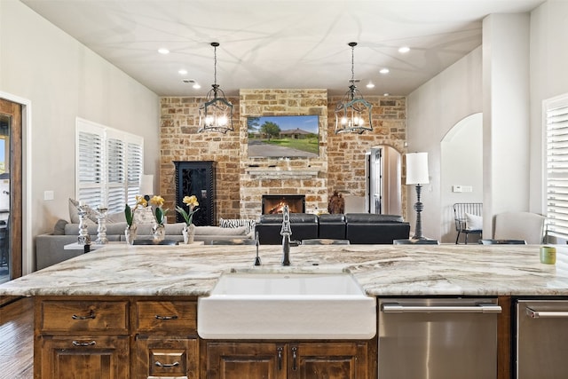 kitchen featuring a stone fireplace, an inviting chandelier, plenty of natural light, and sink