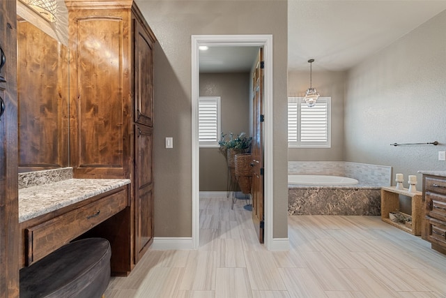 bathroom featuring vanity and tiled bath